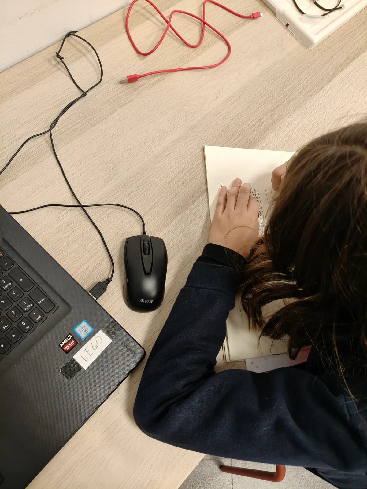 Un miembro del Club dibujando a mano el plano de su proyecto junto al portátil