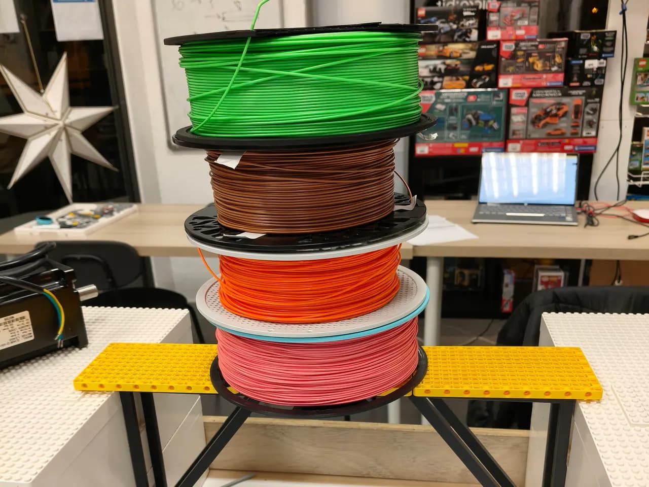 Bobinas de filamento de colores del taller apoyadas sobre una estructura construida en el Club