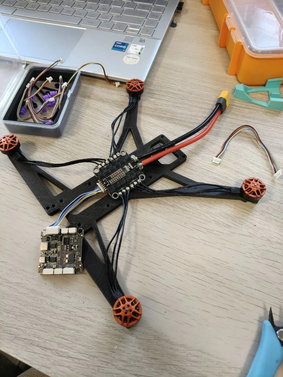 Chasis de dron de fibra de carbono con motores, ESC y controladora cableados sobre la mesa del taller de mecatrónica