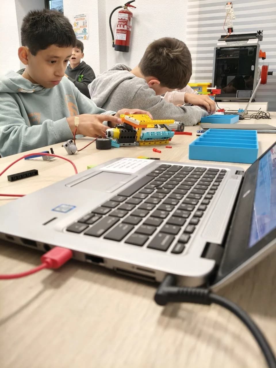 Dos alumnos de LegoWorks montando un robot LEGO con motor y sensores en el aula de robótica de Pamplona